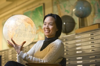 Graduate student Nij Tontisirin with globe in library