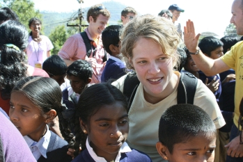 Students mingle with children at a village school in India.