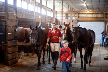 Lizzie Wisner leads horses out of the barn before a match